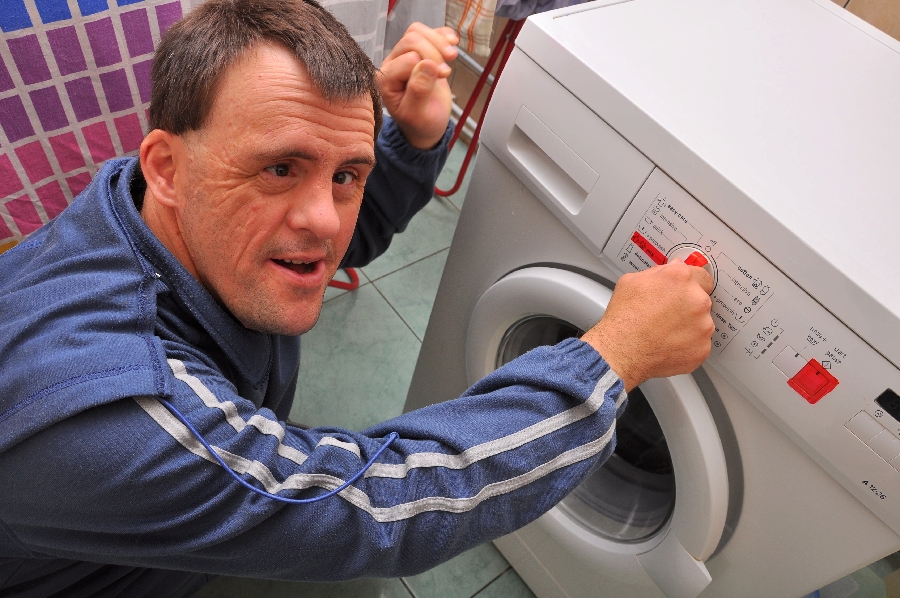 A man with Downs syndrome using a washing machine