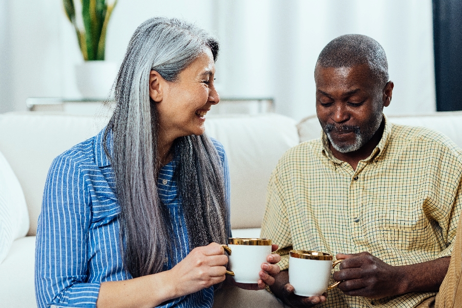A multiethnic senior coupe dipping coffee and sharing a sweet moment together
