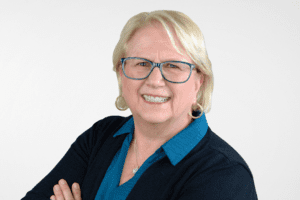 Smiling woman with blond hair in a black jacket and blue dress shirt